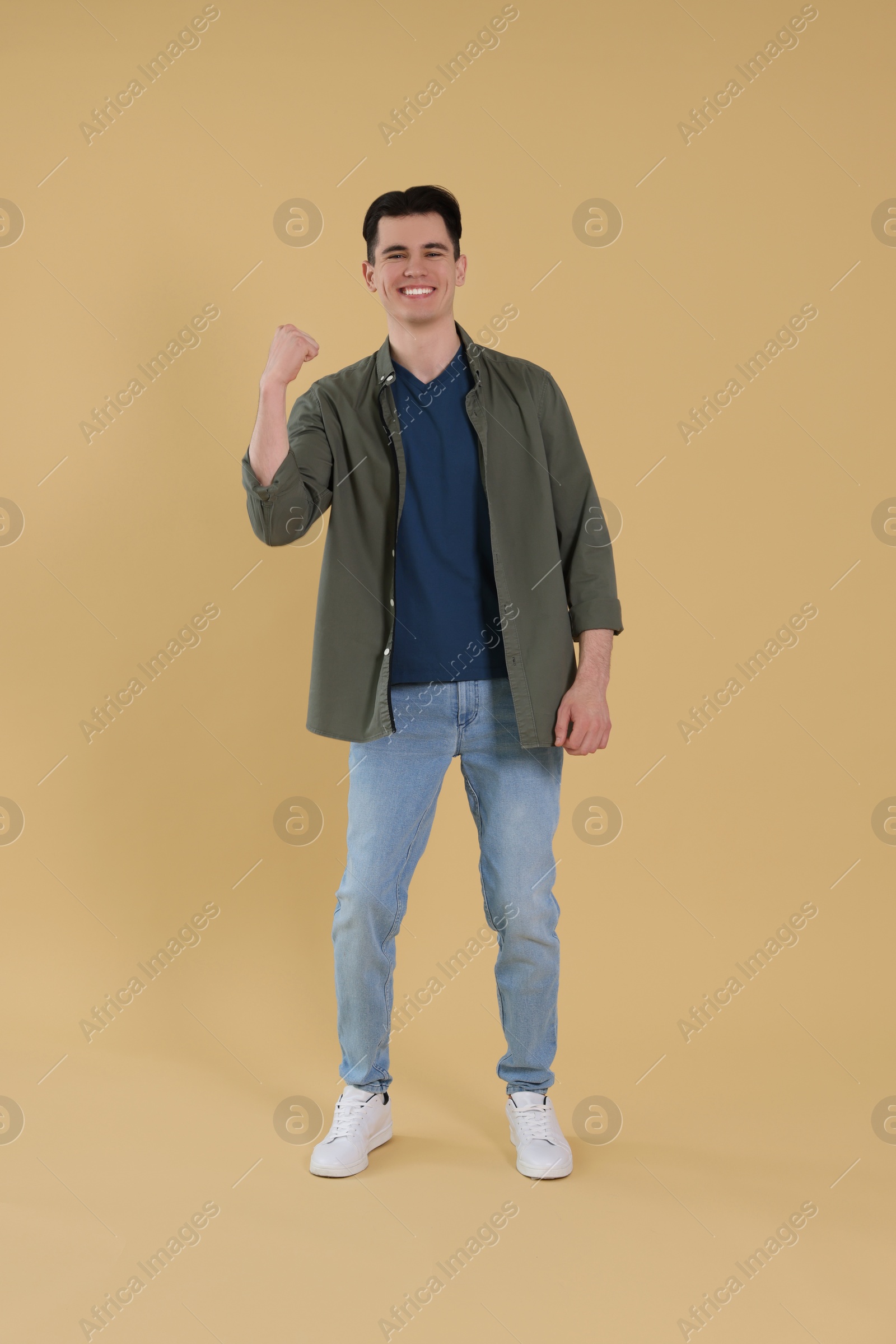 Photo of Full length portrait of happy young man on beige background