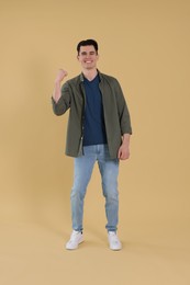 Full length portrait of happy young man on beige background