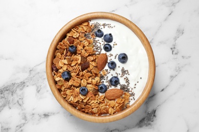 Photo of Tasty homemade granola served on white marble table, top view. Healthy breakfast