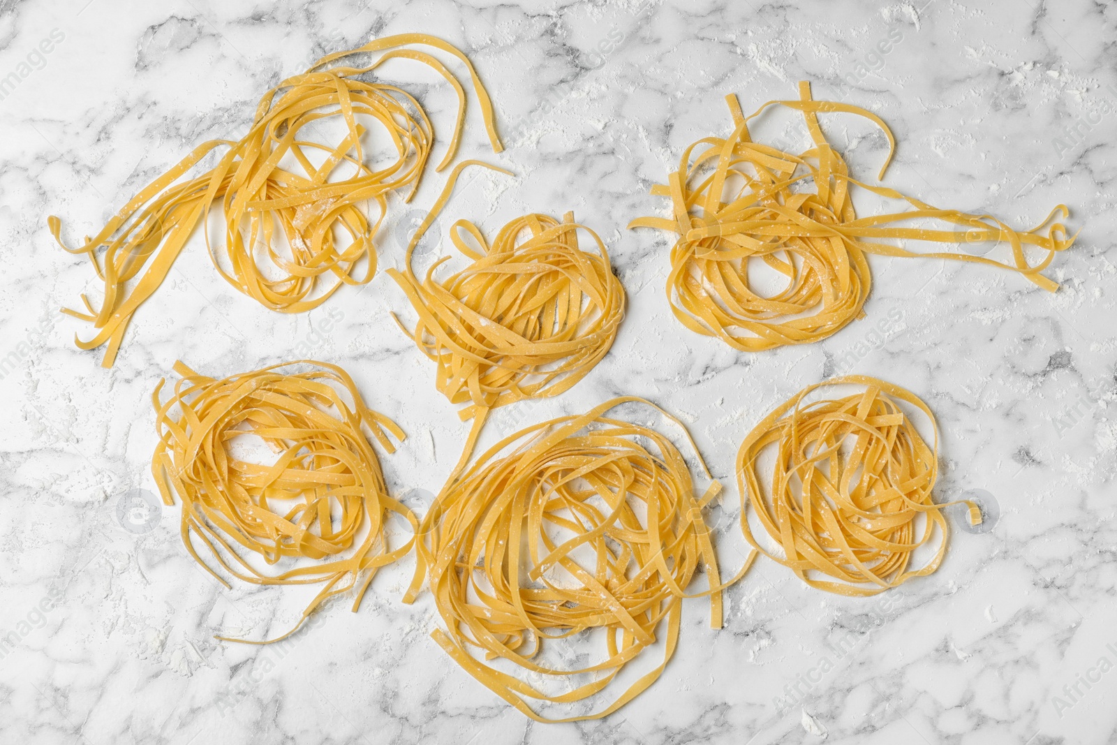 Photo of Raw egg noodles on marble table, flat lay