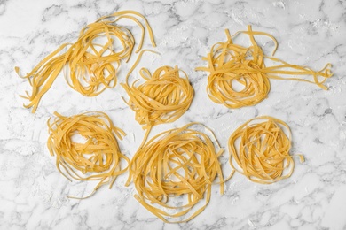 Raw egg noodles on marble table, flat lay