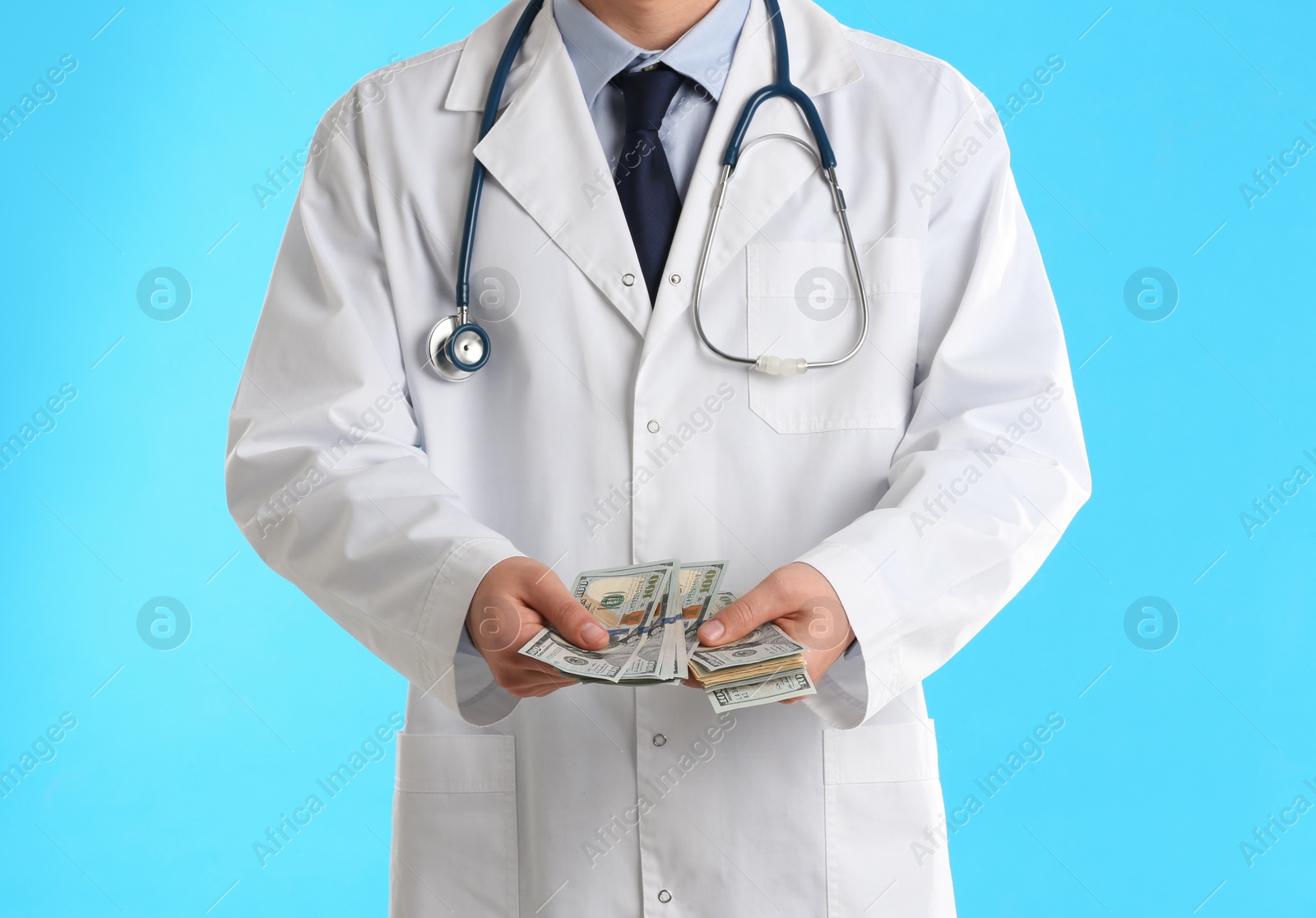 Photo of Doctor with bribe on light blue background, closeup. Corruption in medicine