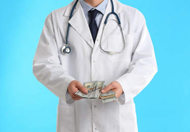 Doctor with bribe on light blue background, closeup. Corruption in medicine