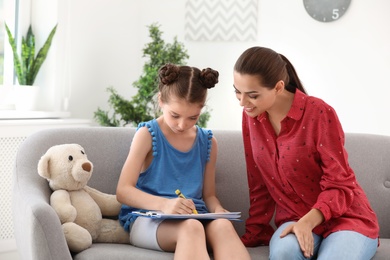 Young female psychologist working with little child in office