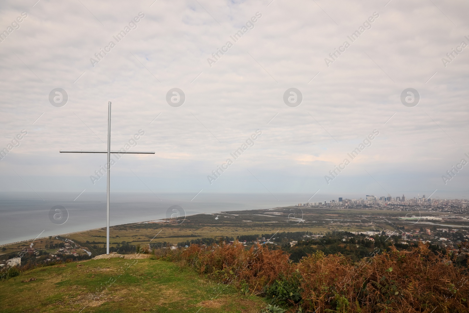 Photo of Picturesque view of city, beautiful sea and old cross under cloudy sky