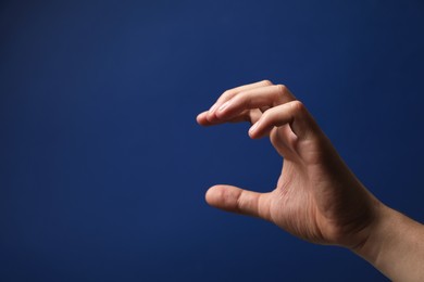 Photo of Man holding something in hand on blue background, closeup. Space for text