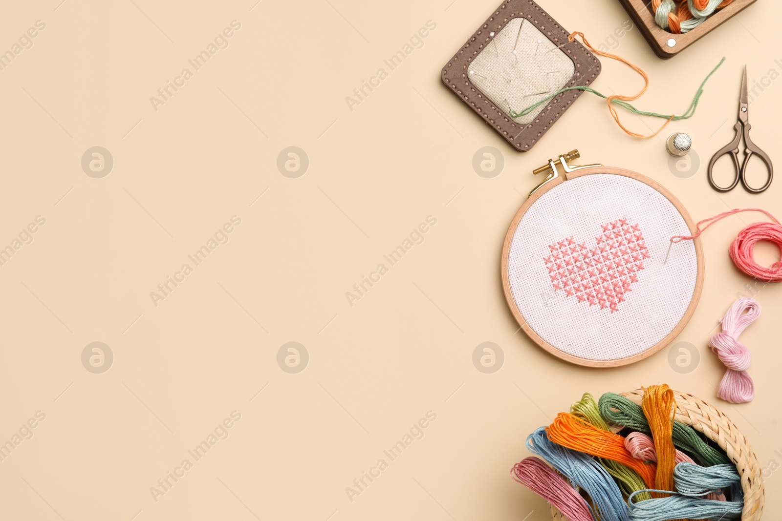 Photo of Flat lay composition with embroidery and different sewing accessories on beige background. Space for text