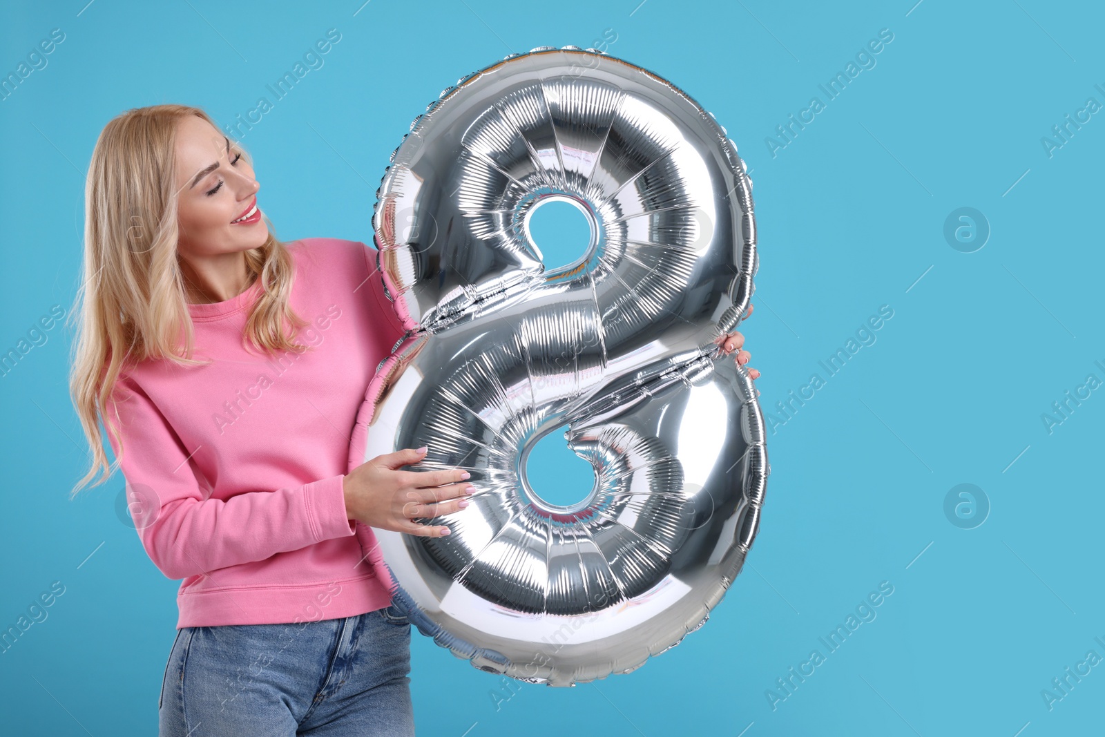 Photo of Happy Women's Day. Charming lady holding balloon in shape of number 8 on light blue background