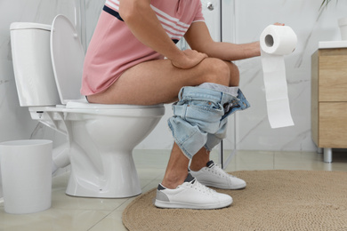 Photo of Man suffering from hemorrhoid on toilet bowl in rest room, closeup