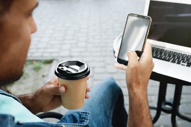 Photo of Man with smartphone and laptop in outdoor cafe, closeup