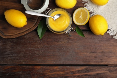 Delicious lemon curd and fresh fruits on wooden table, flat lay. Space for text