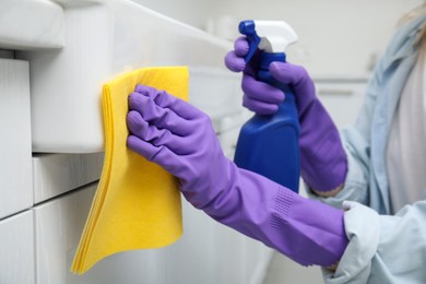 Photo of Woman cleaning white surface with rag and detergent indoors, closeup