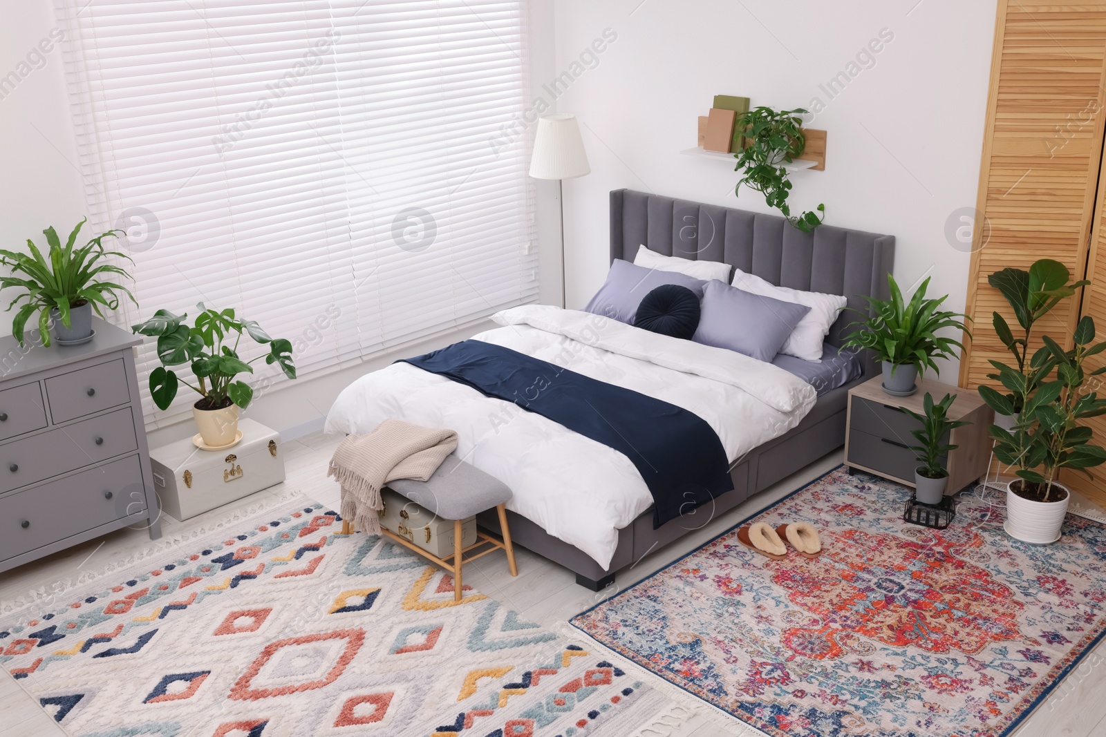 Photo of Stylish bedroom with double bed and beautiful green houseplants, above view. Modern interior