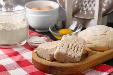 Photo of Compressed yeast, salt, flour, eggs and dough on wooden table