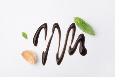 Photo of Organic balsamic vinegar, garlic and basil leaves on white background, flat lay