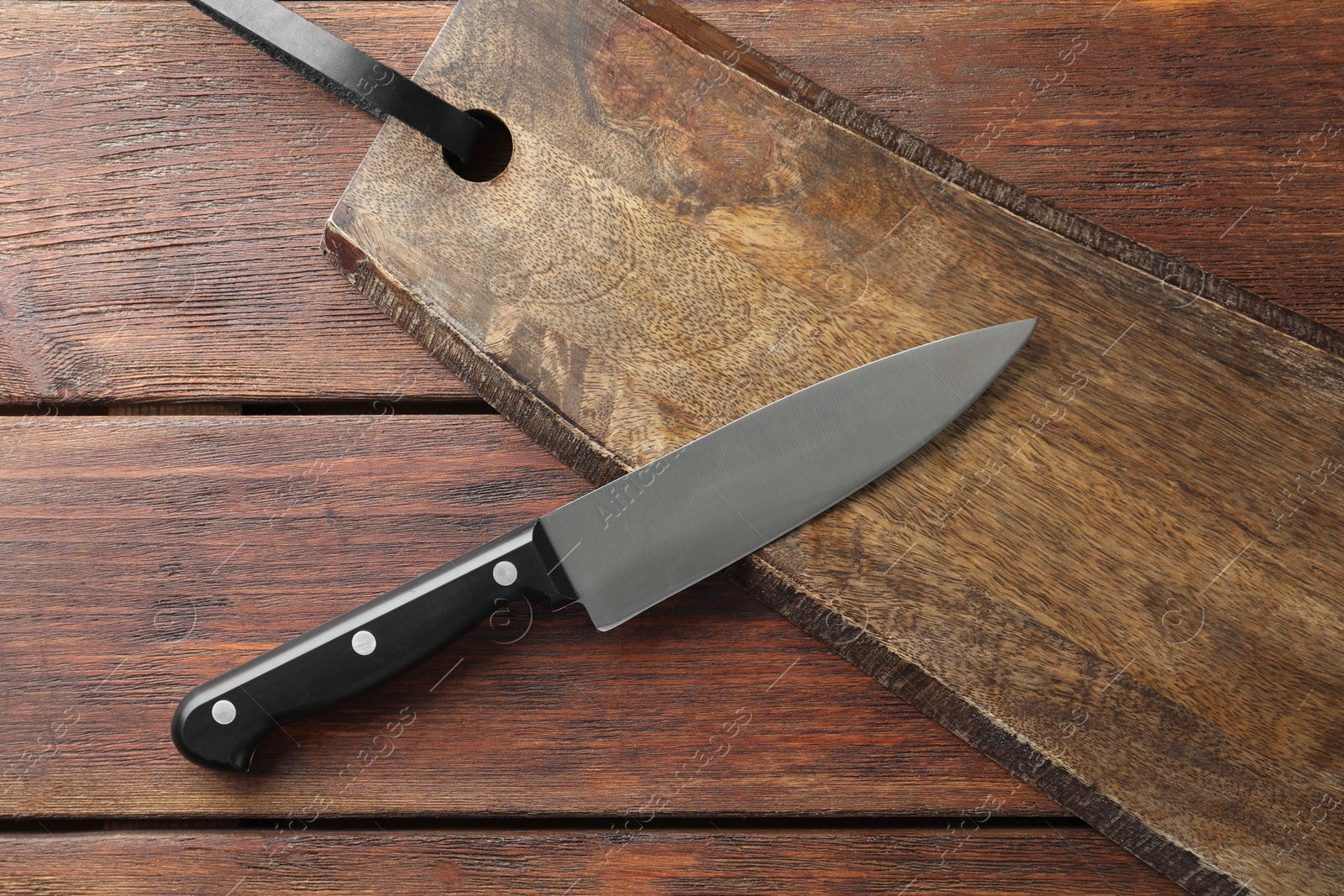 Photo of One sharp knife and board on wooden table, top view