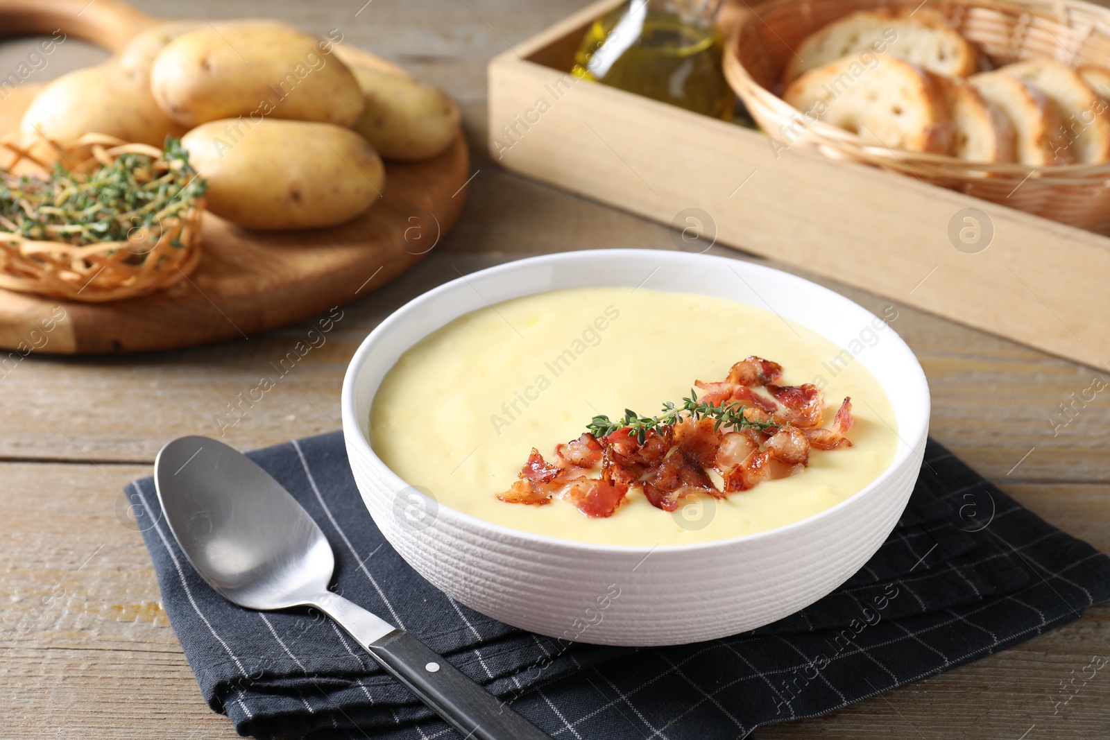 Photo of Tasty potato soup with bacon and rosemary in bowl served on wooden table