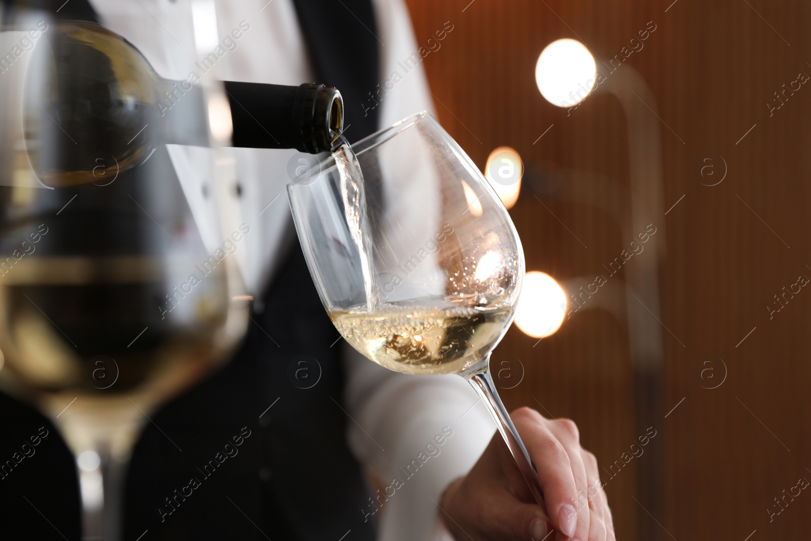 Photo of Waitress pouring wine into glass in restaurant, closeup