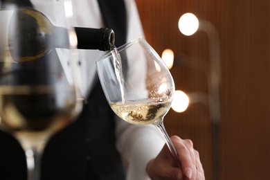 Photo of Waitress pouring wine into glass in restaurant, closeup