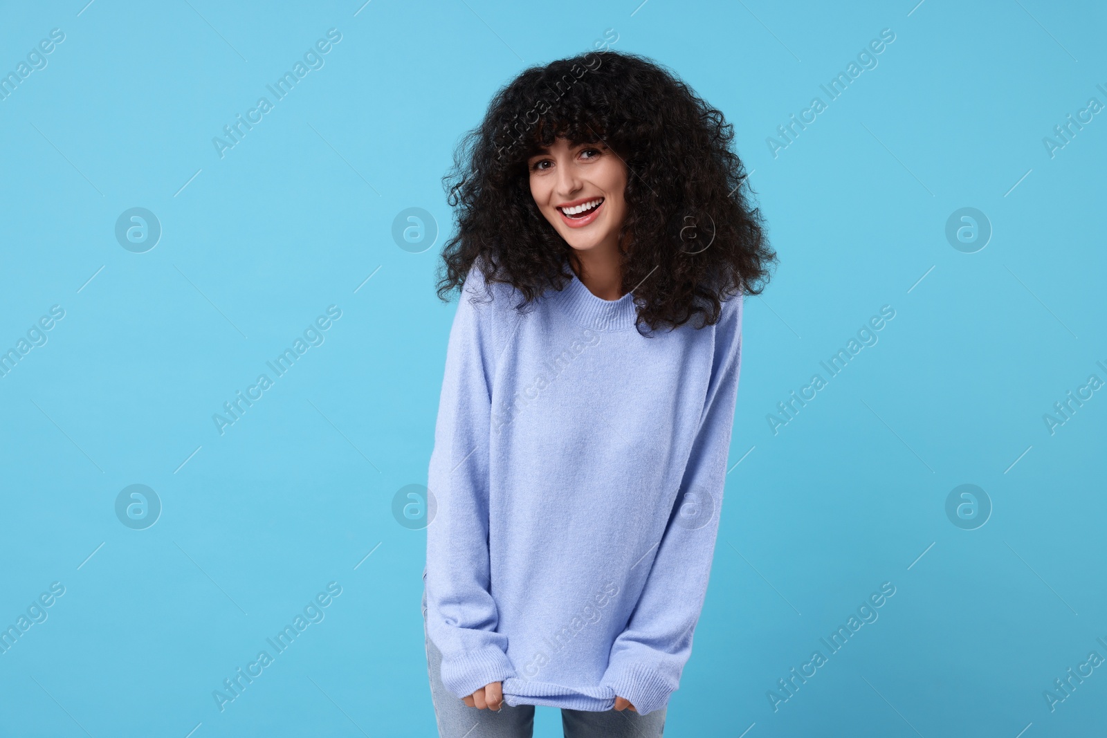 Photo of Happy young woman in stylish warm sweater on light blue background