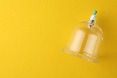 Photo of Plastic cup on yellow background, top view with space for text. Cupping therapy
