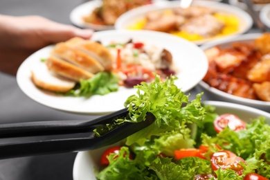 Woman taking food from buffet table, closeup