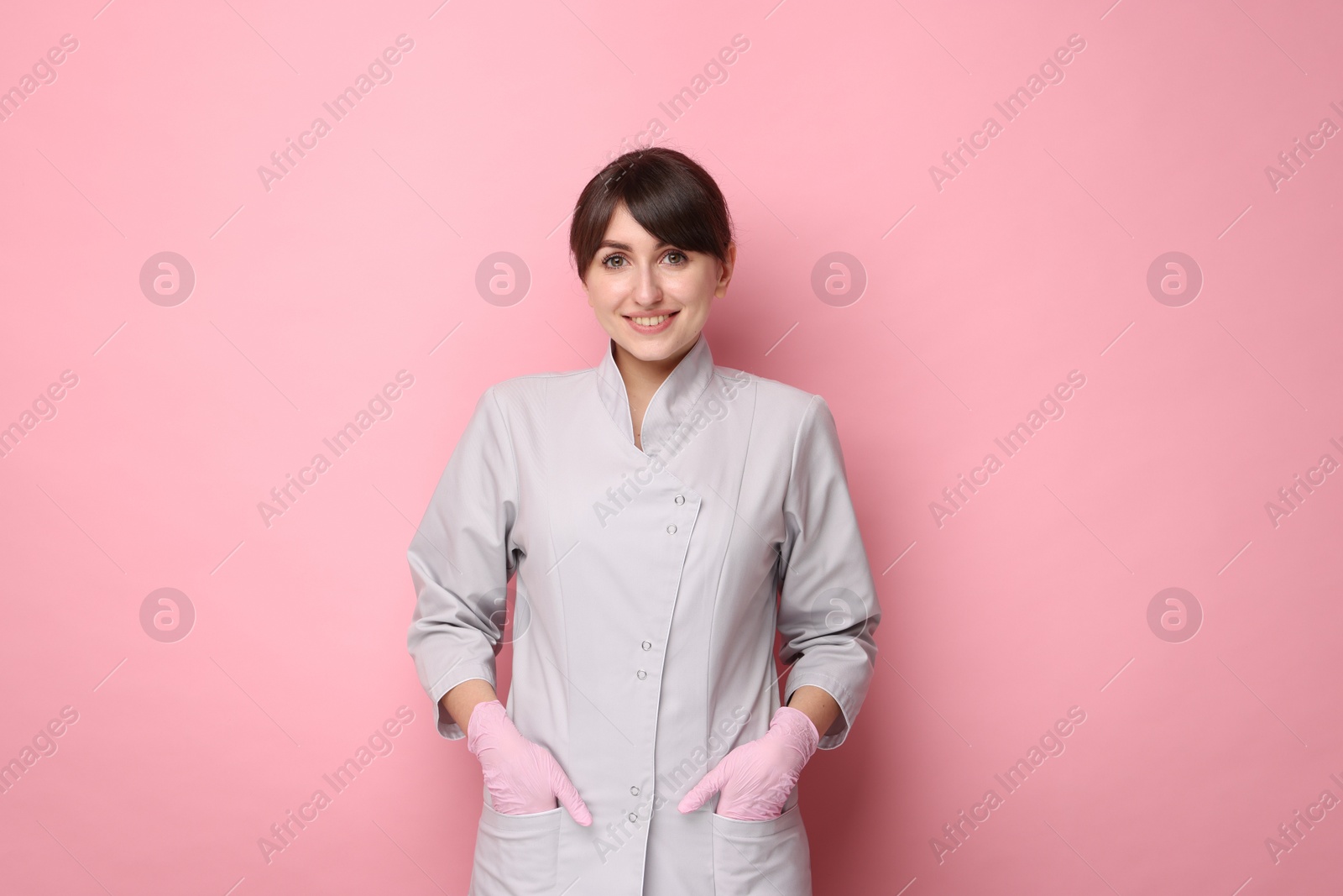 Photo of Cosmetologist in medical uniform on pink background