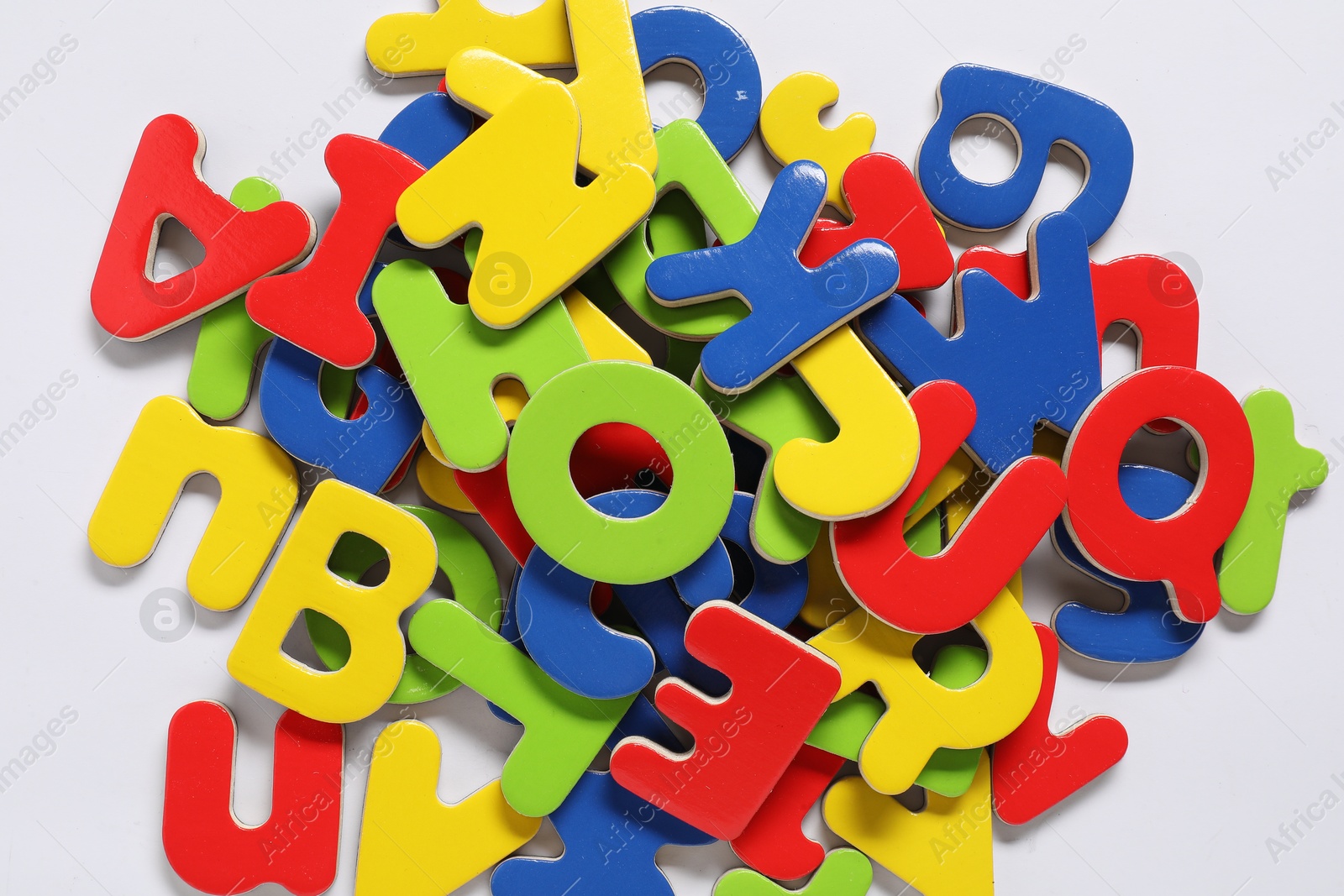 Photo of Learning alphabet. Bright magnetic letters on white background, top view