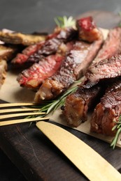 Photo of Delicious grilled beef with rosemary served on wooden board, closeup