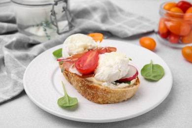 Photo of Delicious sandwich with burrata cheese, ham, radish and tomato served on light grey table, closeup