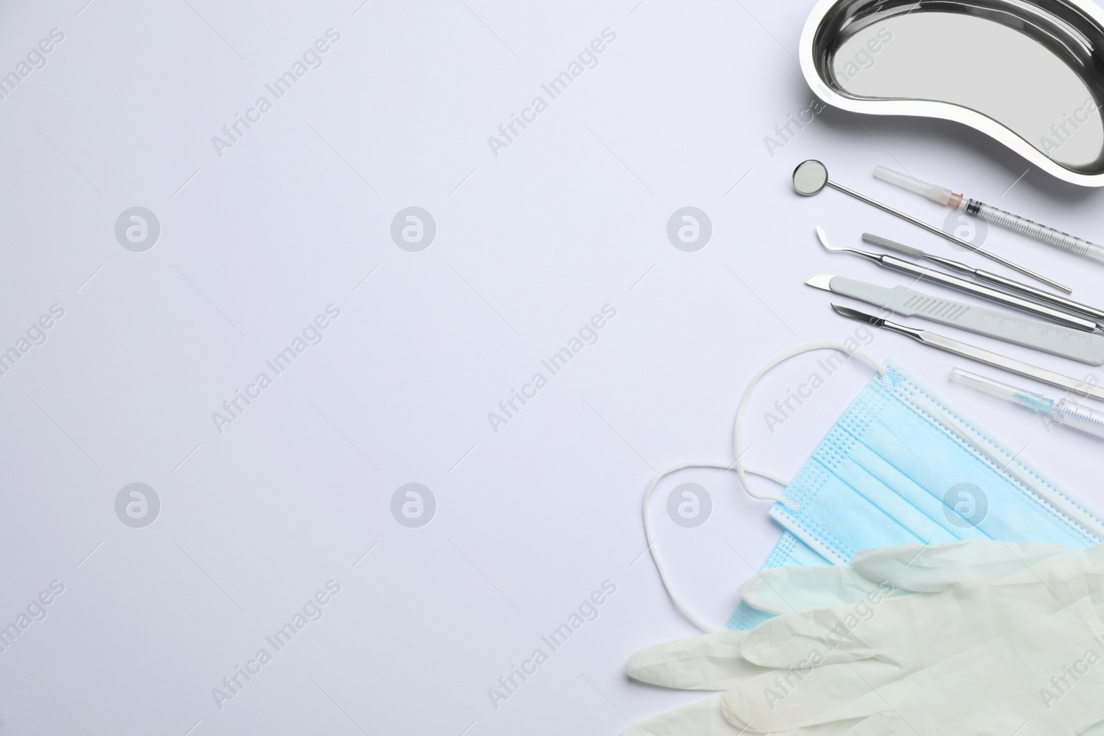 Photo of Set of different dentist's tools, face masks and gloves on light background, flat lay. Space for text