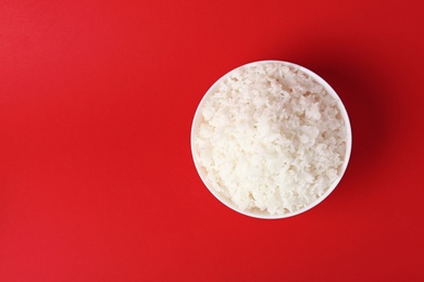 Photo of Bowl of boiled rice on color background, top view with space for text