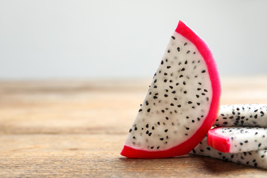Photo of Slices of delicious ripe dragon fruit (pitahaya) on wooden table. Space for text
