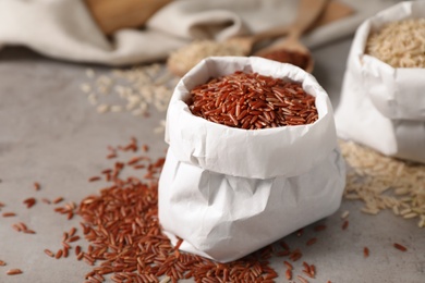 Photo of Uncooked brown rice in paper bag on table. Space for text