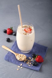 Photo of Tasty yogurt in glass, oats and berries on grey table