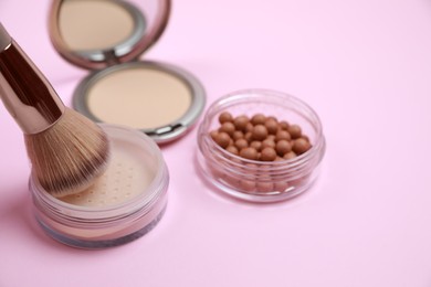 Photo of Applying face powder on brush on pink background. Space for text