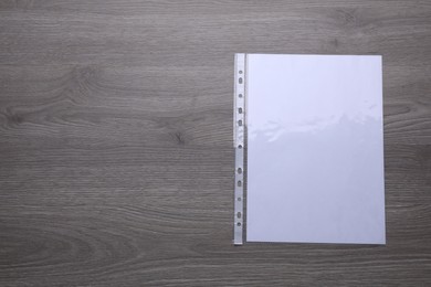 Photo of Punched pocket with paper sheet on wooden table, top view. Space for text