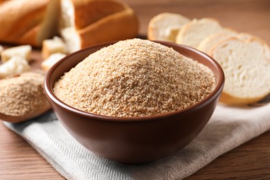 Photo of Fresh bread crumbs in bowl on wooden table, closeup