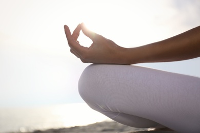 Photo of Young woman practicing zen meditation on beach, closeup. Space for text