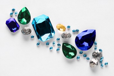 Photo of Different beautiful gemstones for jewelry on white background, top view