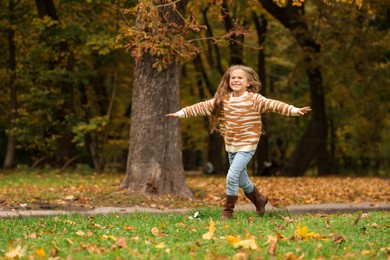 Photo of Happy girl running in autumn park, space for text