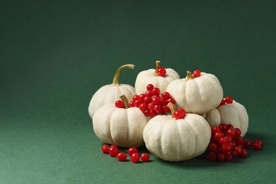 Photo of Happy Thanksgiving day. Beautiful composition with pumpkins and red berries on green background, space for text