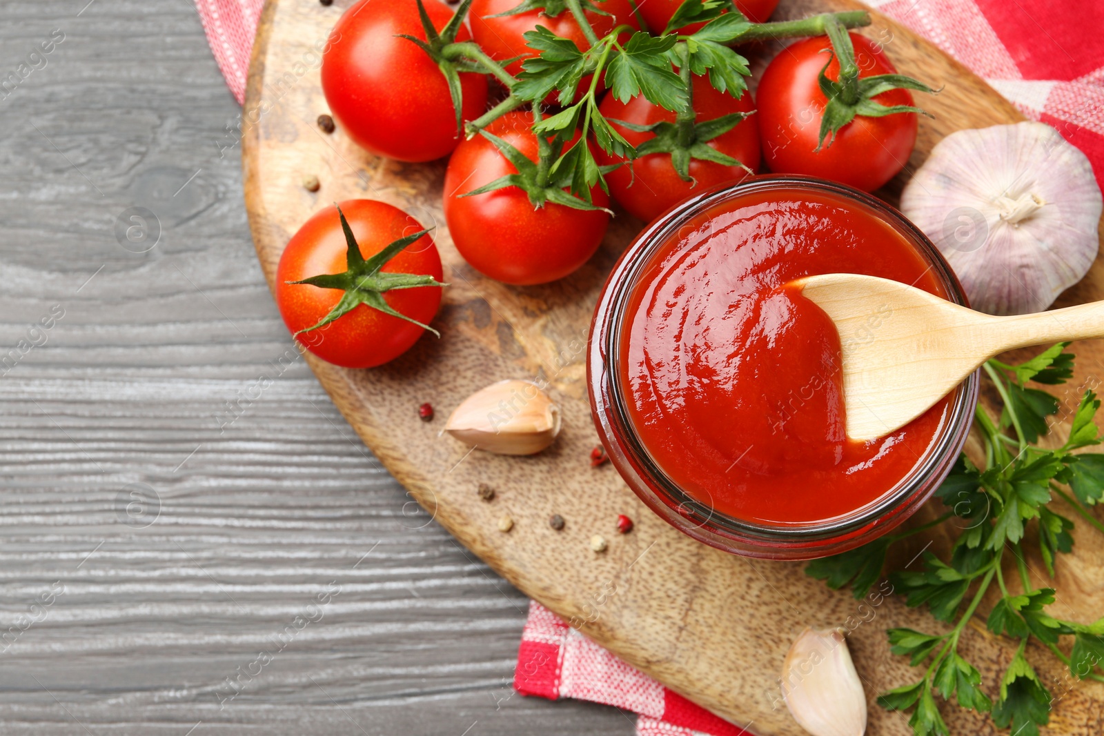 Tasty ketchup, fresh tomatoes, parsley and spices on grey wooden table, flat lay. Space for text Photo of Tasty ketchup, fresh tomatoes, parsley and spices on grey wooden table, flat lay. Space for text