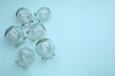 Photo of Glass cups on light blue background, flat lay and space for text. Cupping therapy