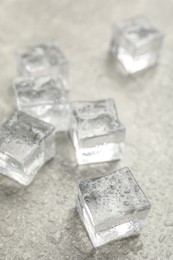 Photo of Ice cubes with water drops on light stone table