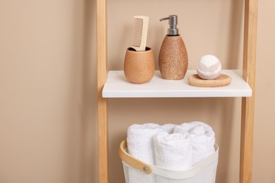 Photo of Different bath accessories and personal care products on shelving unit near beige wall