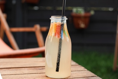 Photo of Bottle of tasty lemonade on wooden table