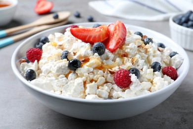 Photo of Delicious cottage cheese with fresh berries served for breakfast on light grey table, closeup