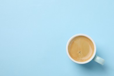 Photo of Aromatic coffee in cup on light blue background, top view. Space for text