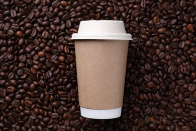 Photo of Coffee to go. Paper cup on roasted beans, top view